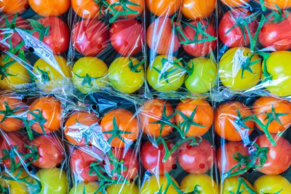 Display of fresh plastic wrapped yellow, orange and red cherry tomatoes